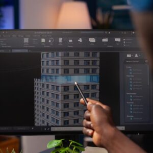 an architect-engineer pointing at an architectural building prototype on a PC screen