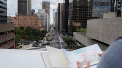 a person looking at an architectural project in a notebook, with a city landscape in the background