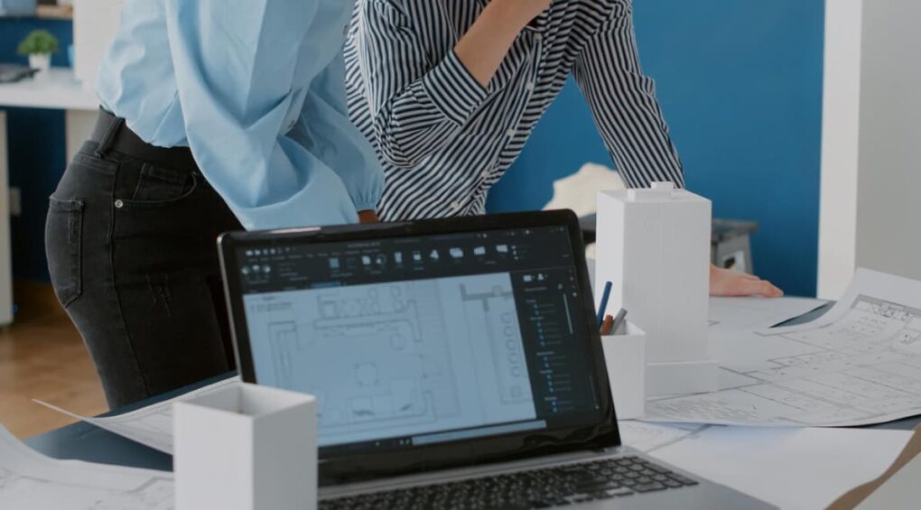 Close-up of an architectural workspace with a laptop and models