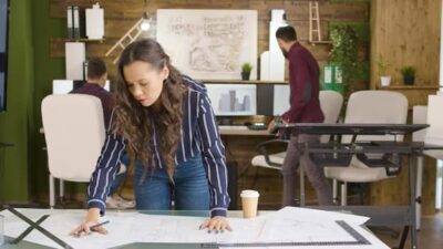 Girl fixing blueprints with a cup of coffee